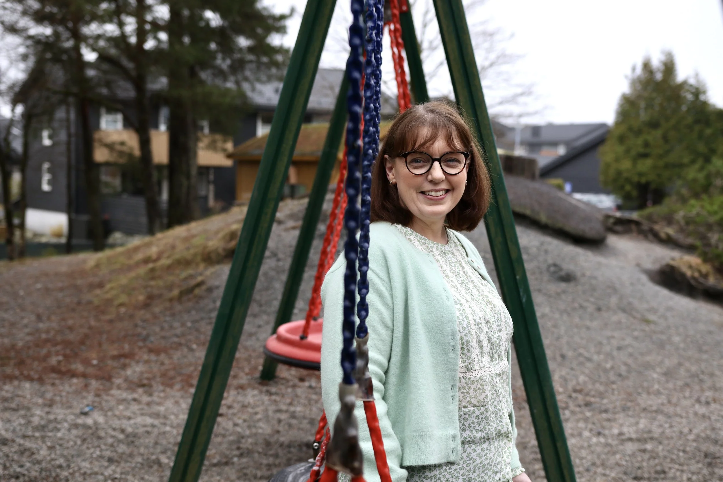 Dame som sitter i en huske i en barnehage