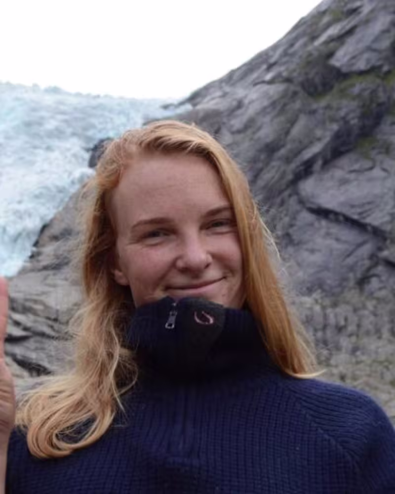 Young woman with red hair smiles in front of a glacier