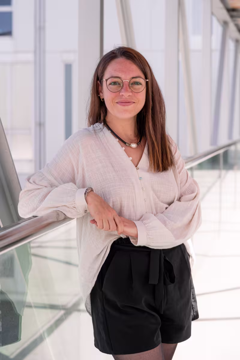 Young woman with long dark hair and glasses smiles at camera