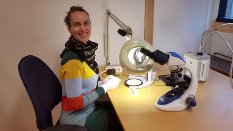 Woman studies archaeological findings through a microscope