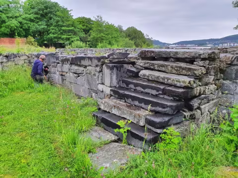 Arkeolog undersøker mur i kirkeruin