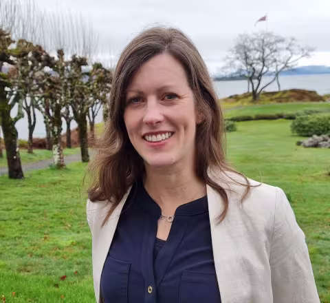 Portrait photo of Lydia outside in a park with fjord view background.