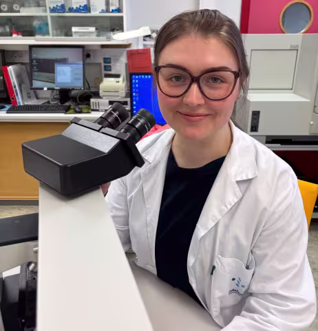 Ulrikke sitting in the lab in front of the microscope.