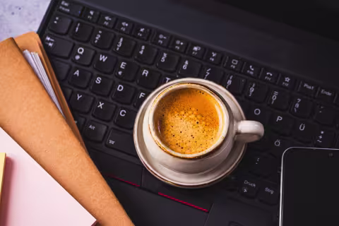 Kaffekopp på datamaskin med dokumenter.