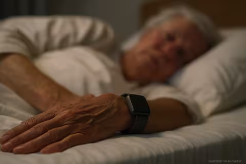An old person sleeping, having a digital sensor wristband on.