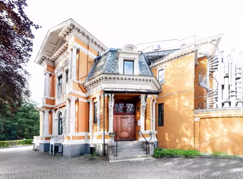 Fronten av en villa i oransjetoner og hvitt