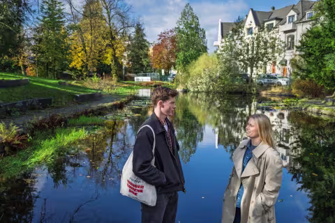 Students talking in front of a pond
