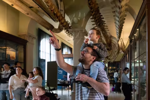 Bilde av far med sønn på skuldrene. De peker nysgjerrig på noe i taket over dem.