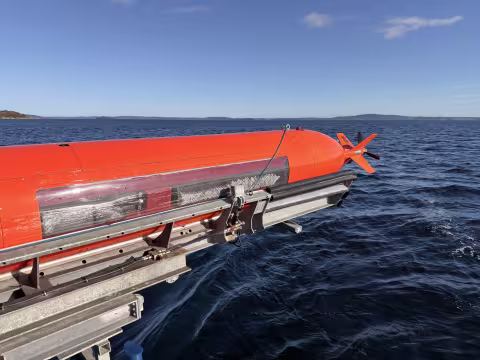 An orange AUV on a rig over the sea