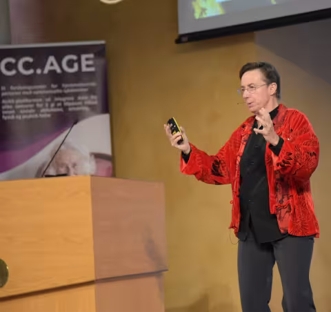 Heather Allore as a speaker on stage on an UiB event enthusiastically talking about something.