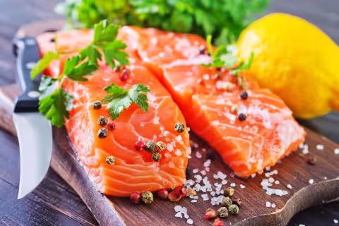 Salmon fillet on a cutting board with salt, spices and lemon
