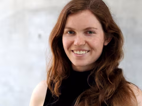 Young woman with long dark hair smiling at camera