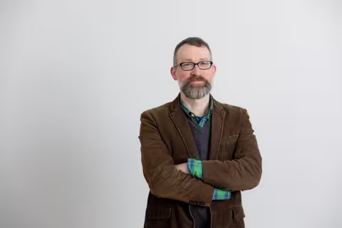 Bildet viser forskeren. En mann med briller og brun blazer. 