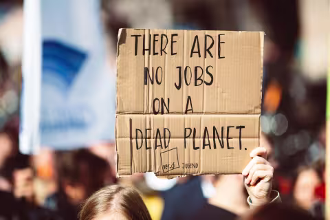 Someone holding as sign that says "there are no jobs on a dead planet"