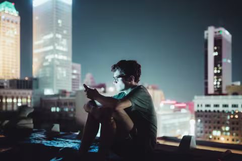 mann i bylandskap som holder mobilitelefon