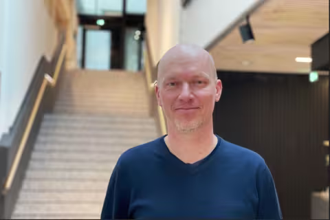 Mann i blå skjorte foran en trapp