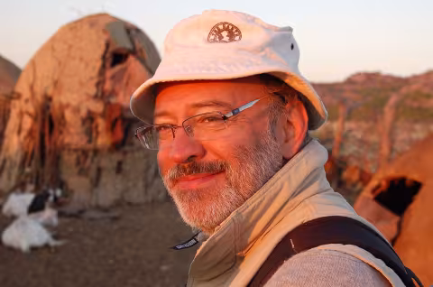 Professor Francesco d’Errico sapience researcher in the filed smiling to camera with rock mountain in the back.