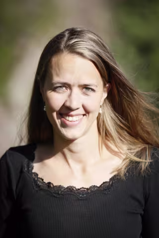 Kvinne som smiler med langt, brunt hår.