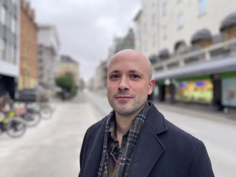 Skallet ung mann ser inn i kamera