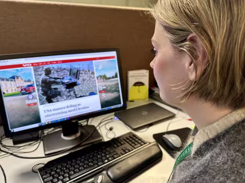 Kvinne ser på skjerm med medieklipp om krig og krise