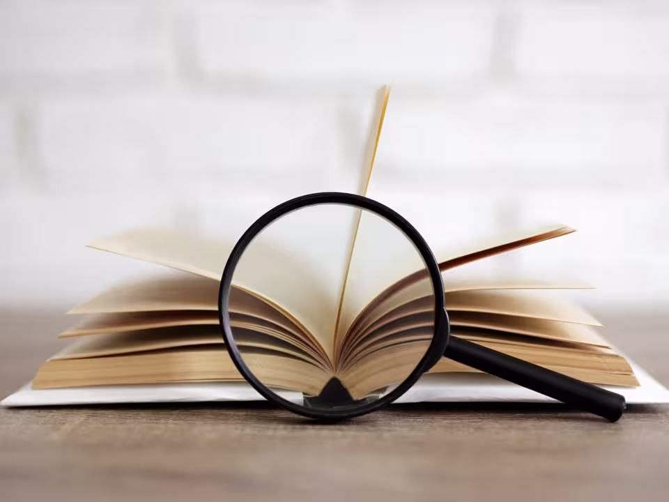 Illustrasjonsbilde av en åpen bok med et forstørrelsesglass liggende foran. 