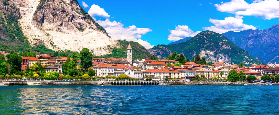A beautiful Italian town on the foot of steep mountains with a lake in front.