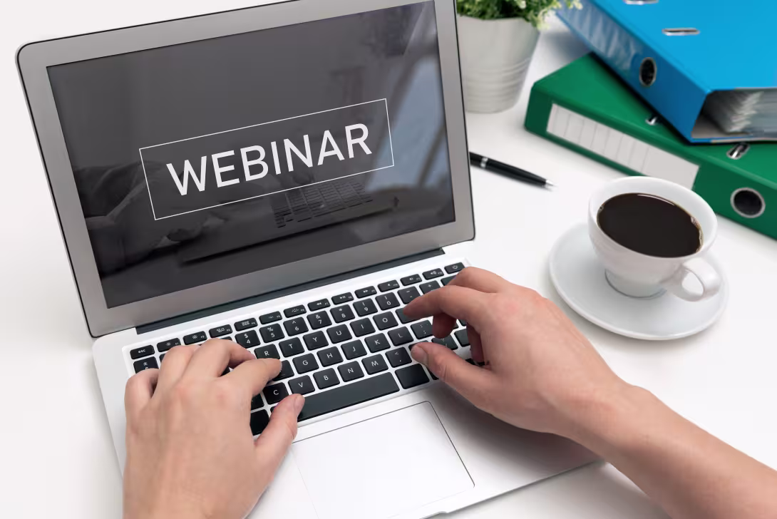 laptop med teksten webinar to hender og kaffekopp