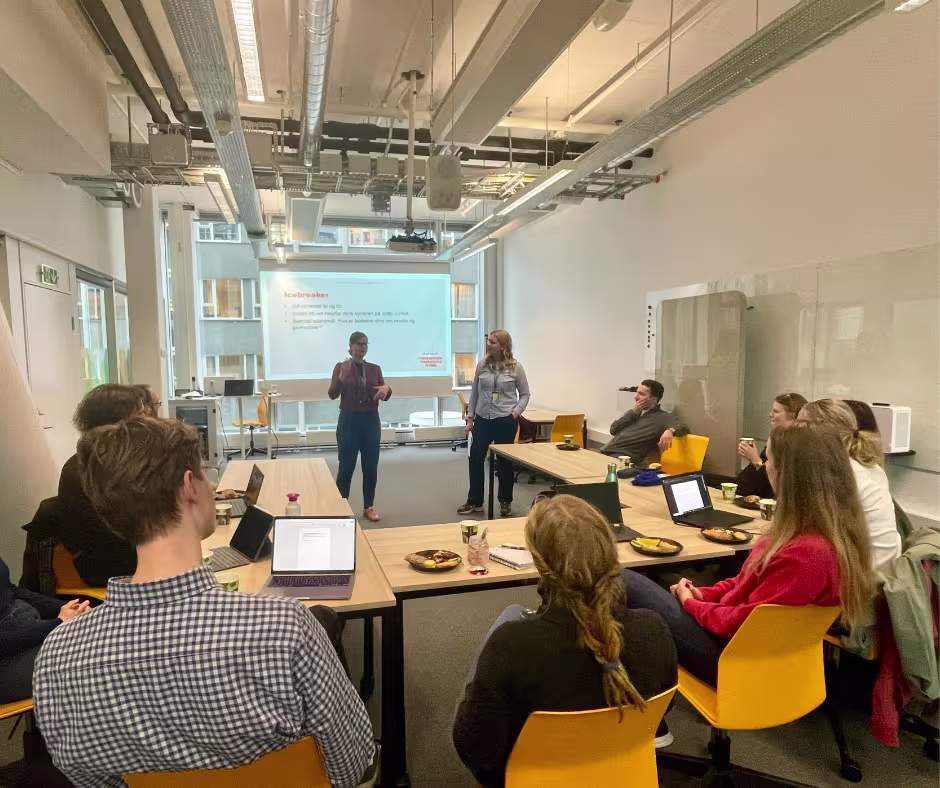 Group of people in a meeting room. Two women are giving a presetation