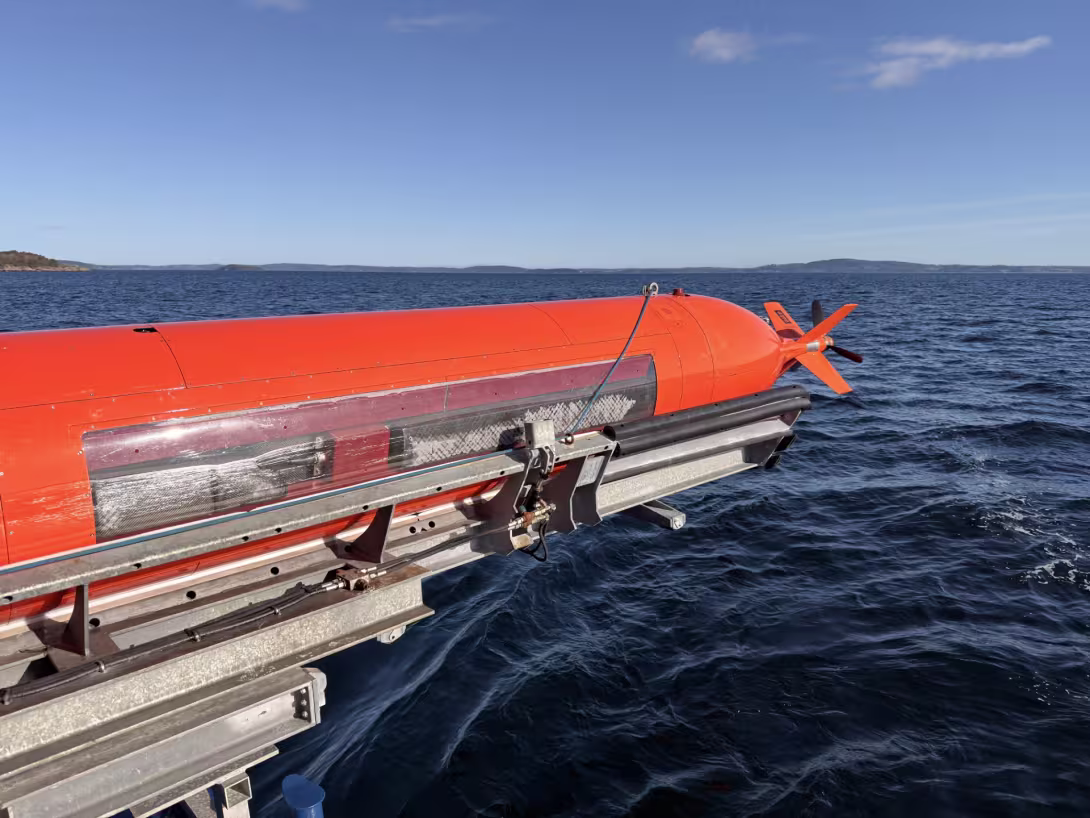 An orange AUV on a rig over the sea