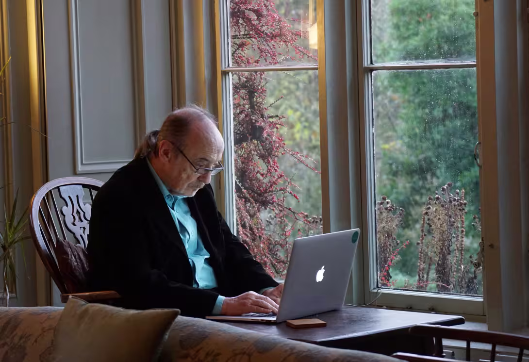 elderly man sits by laptop