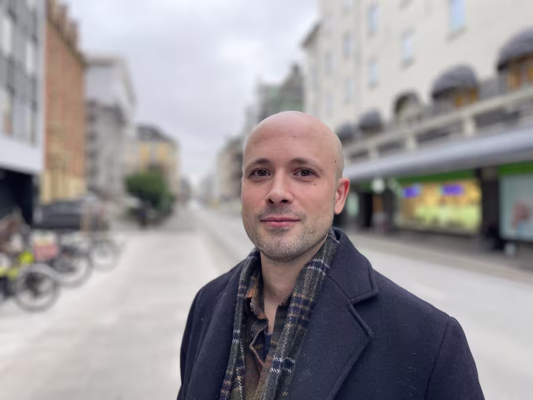 Skallet ung mann ser inn i kamera