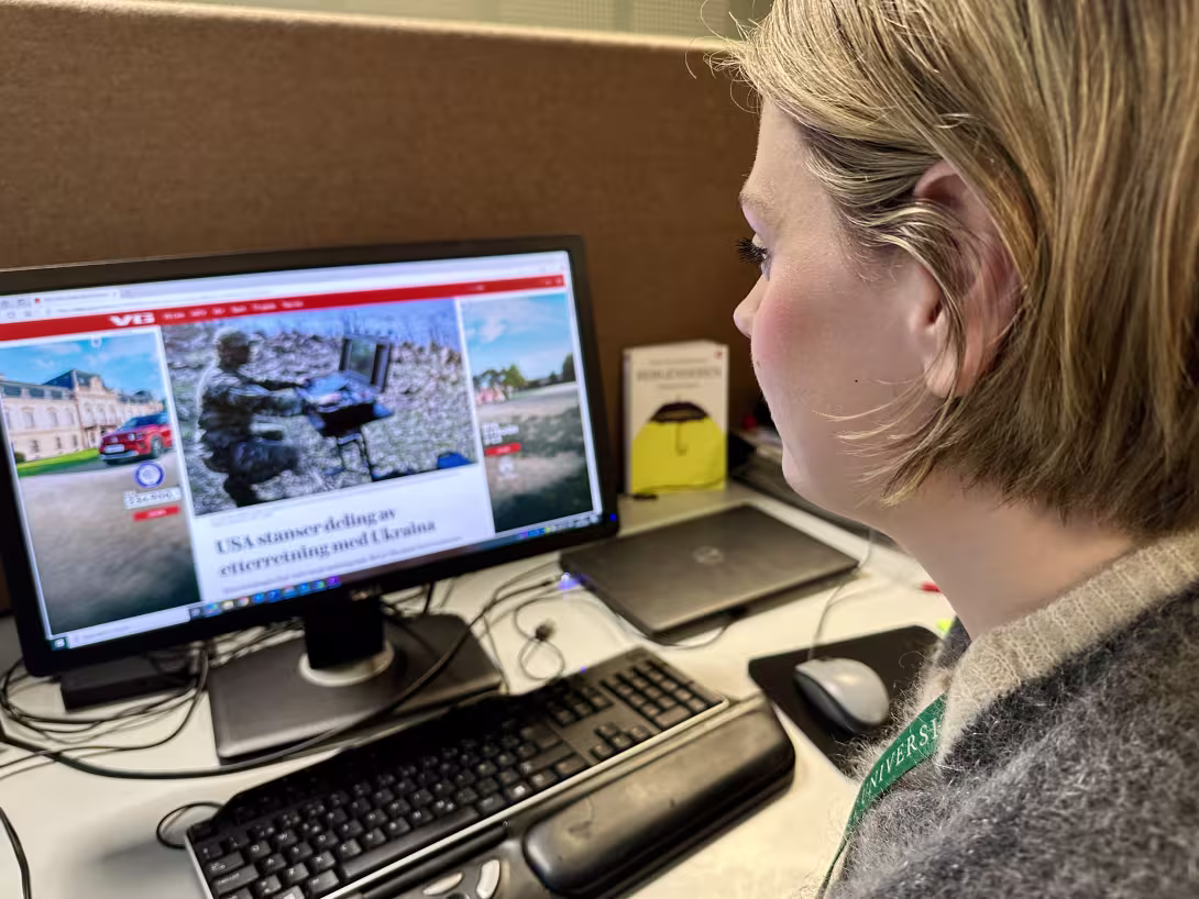 Kvinne ser på skjerm med medieklipp om krig og krise